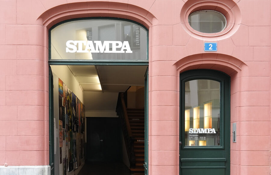 Entrance to a pink building with a green door and a sign that reads STAMPA.