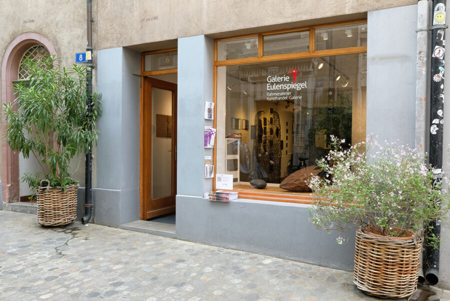 Storefront of Galerie Eulenspiegel with a large window, wooden door, and potted plants.