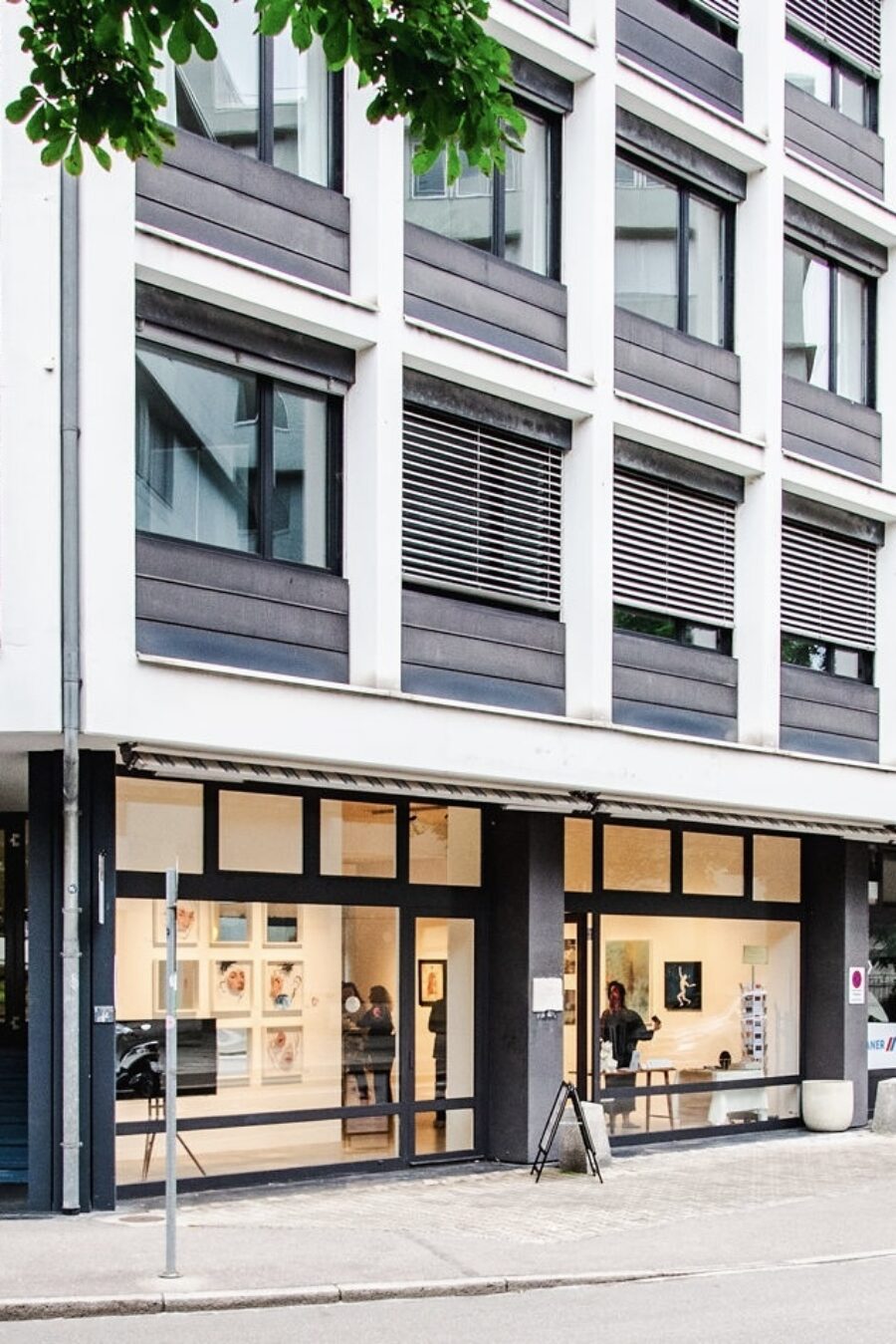 Moderne Geschäftsfassade mit einer Kunstgalerie im Erdgeschoss eines grauen Gebäudes.