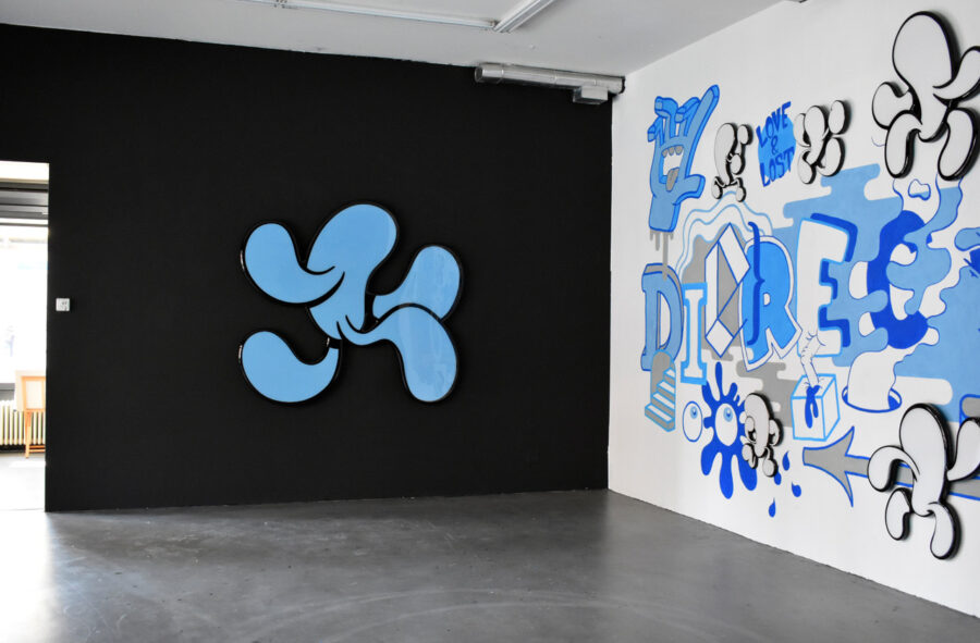 Moderne Kunstinstallation in einem Raum mit einer schwarzen Wand und einem blauen Graffiti-Wandbild.