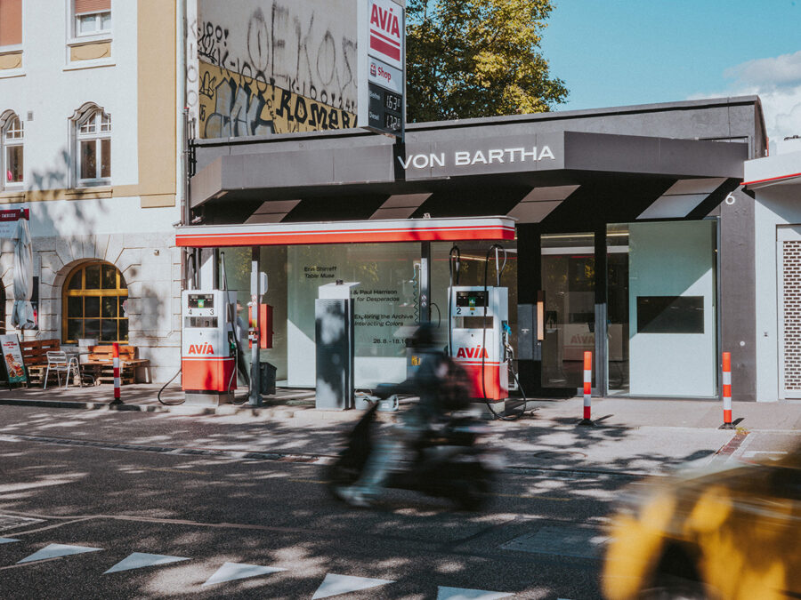 A street scene featuring a modern Avia gas station with a blurred scooter passing by.