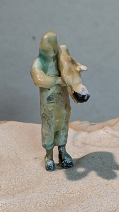 Kleine, abstrakt geformte Keramikfigur einer Person, die ein Tier im Arm hält.