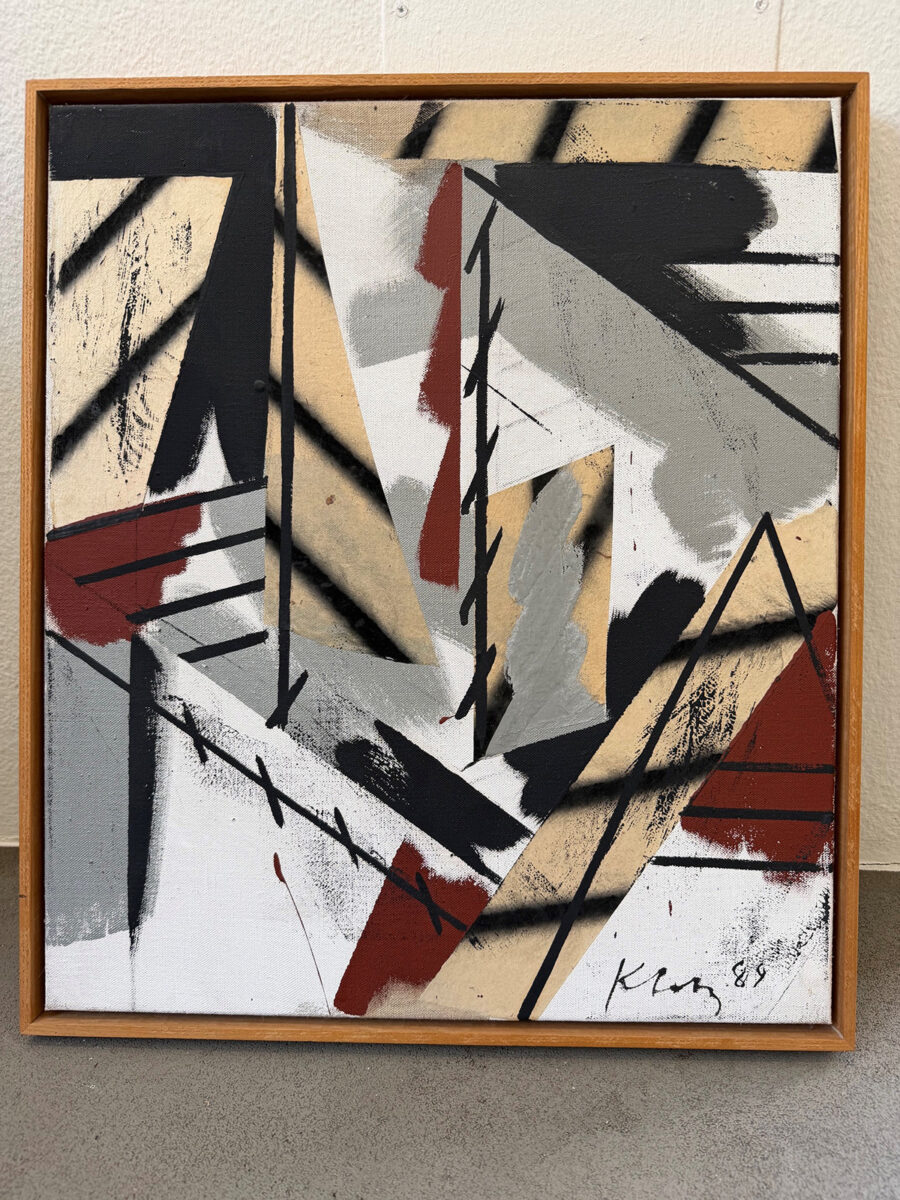 Abstract painting with sharp geometric shapes in black, grey, beige, and red in a wooden frame.