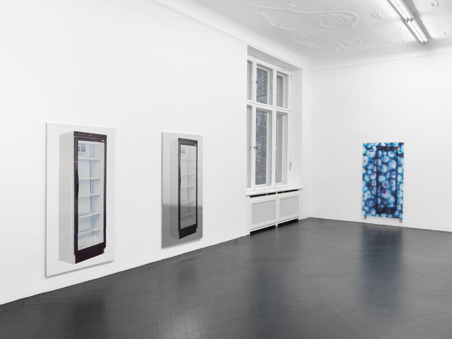 Ein heller Galerie Raum mit zwei Bildern von Kühlschränken und einem blauen abstrakten Kunstwerk.