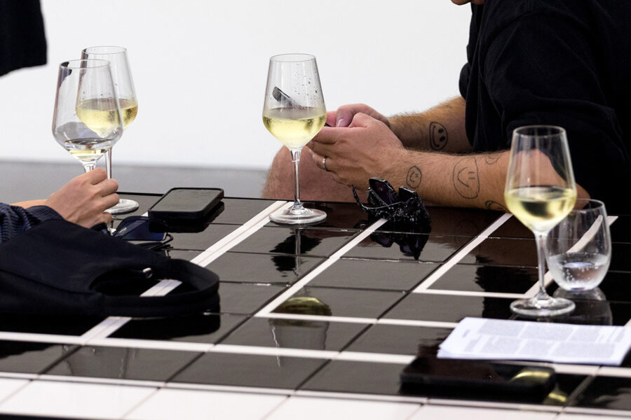 Mehrere Gläser mit Weißwein stehen auf einem glänzenden, schwarz-weißen Tisch.