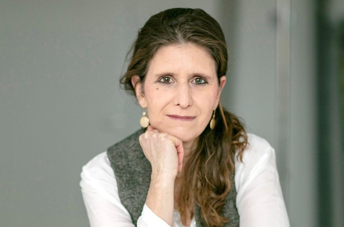 Porträt einer Frau mit braunen Haaren, die nachdenklich ihr Kinn auf die Hand stützt.