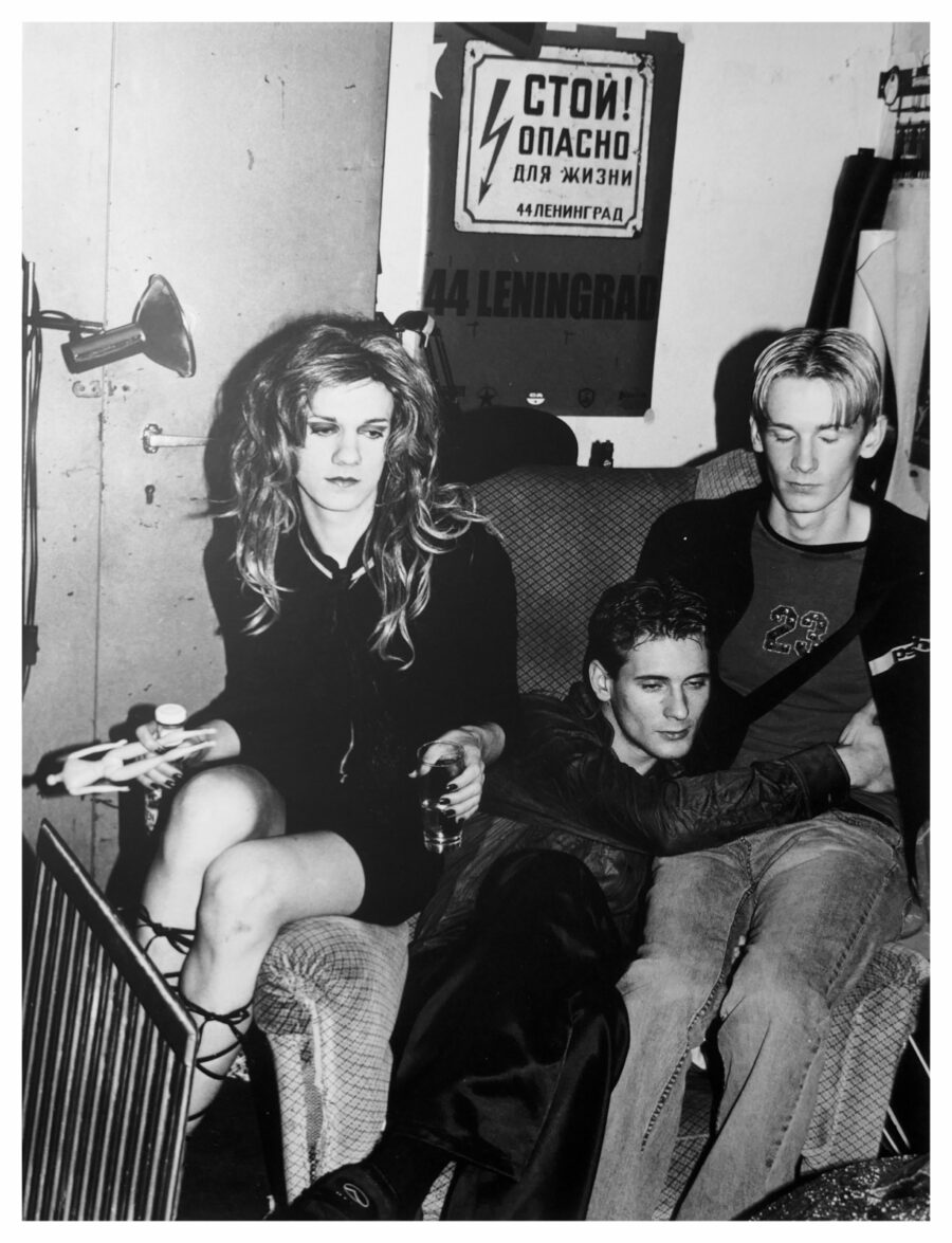 Black and white photo of three young people sitting together in a dimly lit room.
