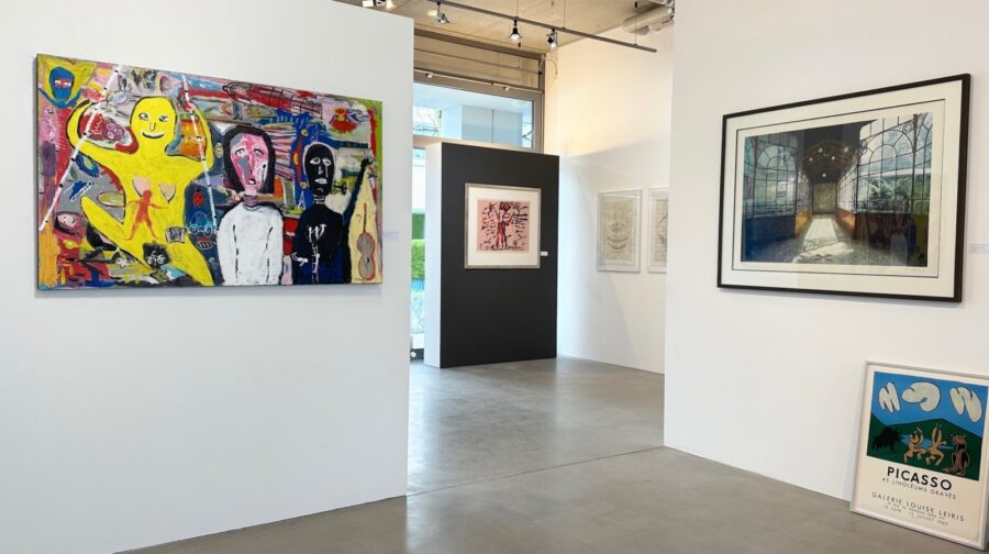 An art gallery interior with several framed colorful paintings on white walls.