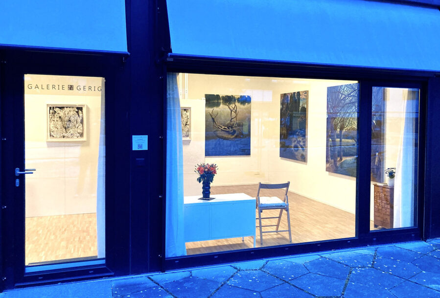 Exterior view of an art gallery storefront with paintings displayed inside.