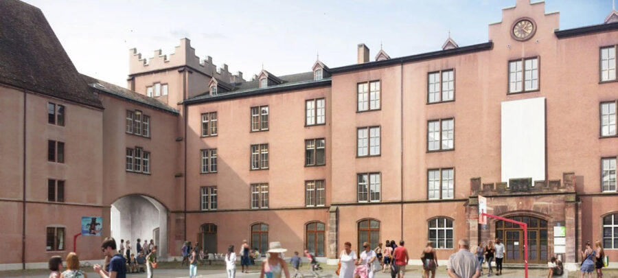 Mehrstöckige, rosa Gebäude mit vielen Fenstern und Menschen auf einem Innenhof.