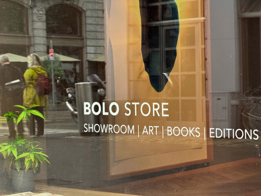 A glass storefront window with the text BOLO STORE SHOWROOM | ART | BOOKS | EDITIONS.