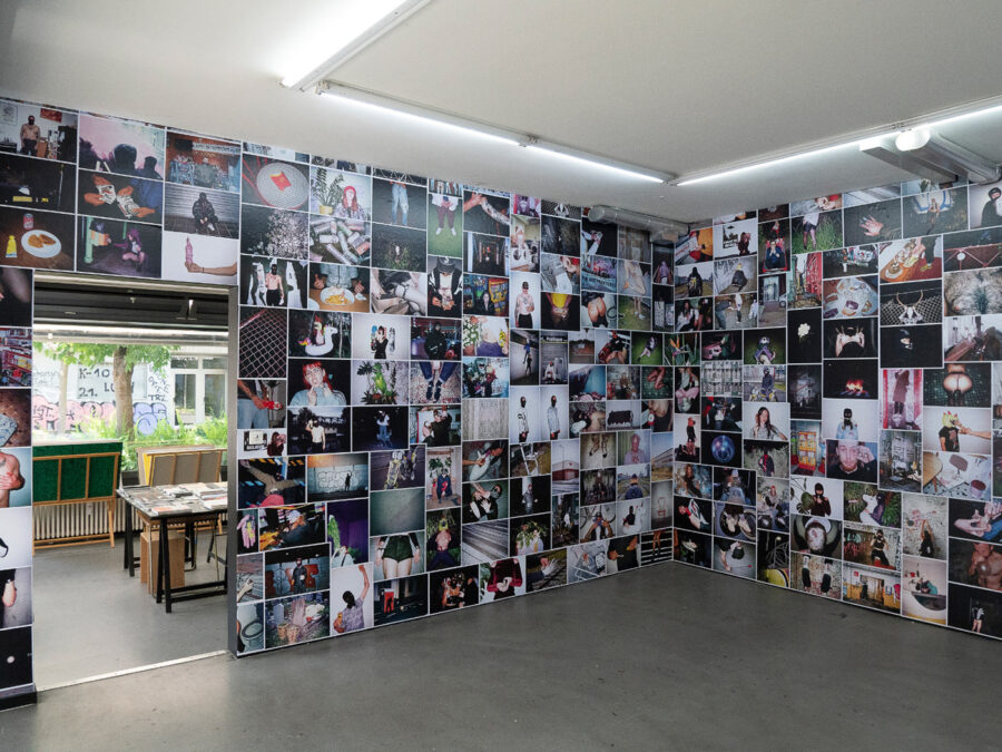 A room with walls completely covered in a grid of diverse photographs.