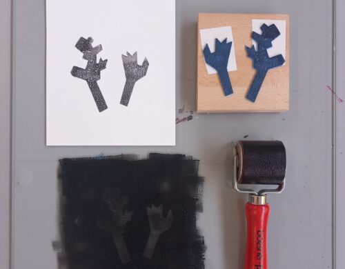 Linocut tools including a carved block, a black print on white paper, and a brayer roller.