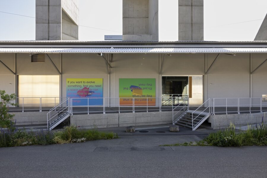 Modern building facade with two colorful text panels and stairs leading to an entrance.