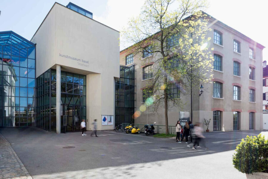 Exterior view of the Kunstmuseum Basel with a modern glass entrance and a classic stone building.