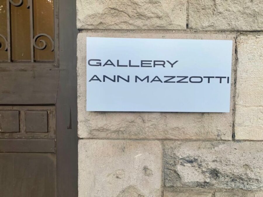 A white rectangular sign on a stone wall reads GALLERY ANN MAZZOTTI in black capital letters.